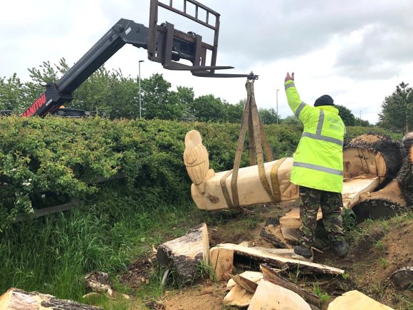 Carved oak bench being lifted by crane